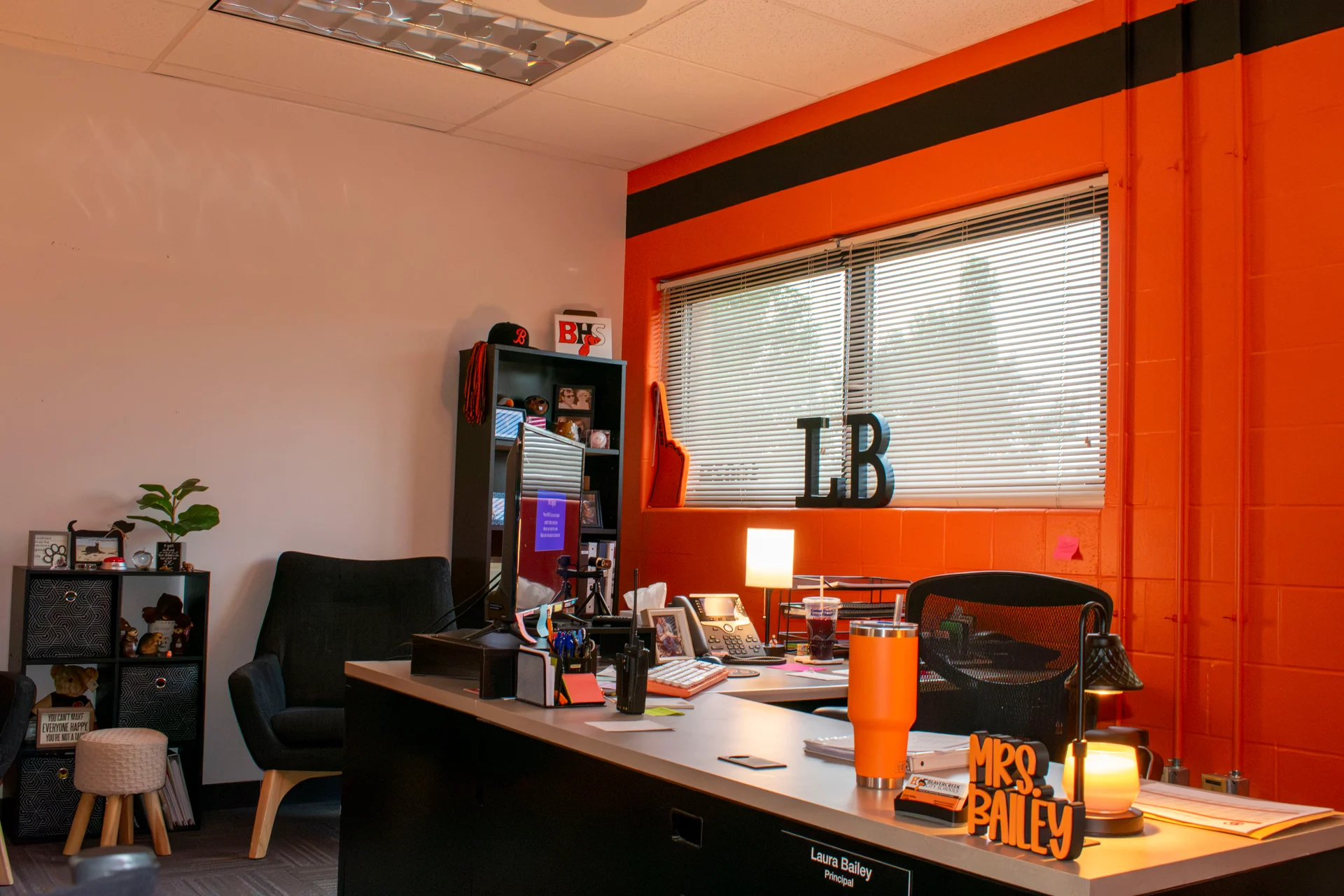 Principal's desk and shelving against fresh orange paint and an interior window in the remodeled Beavercreek office