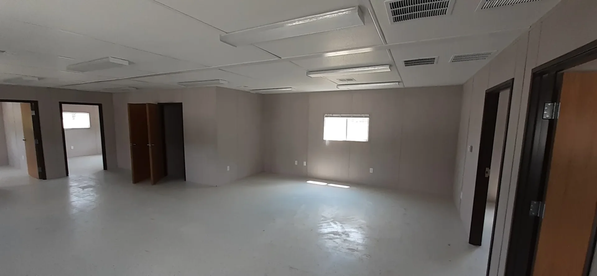 Open classroom space inside the Greeneview modular building, with white wall panels, tile floor and wood doors