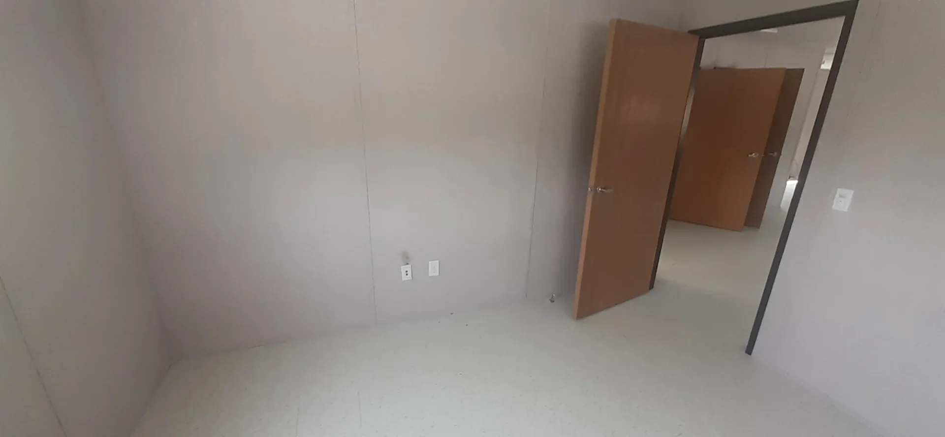 Corner of a Greeneview modular classroom showing an open wood door into the adjoining room