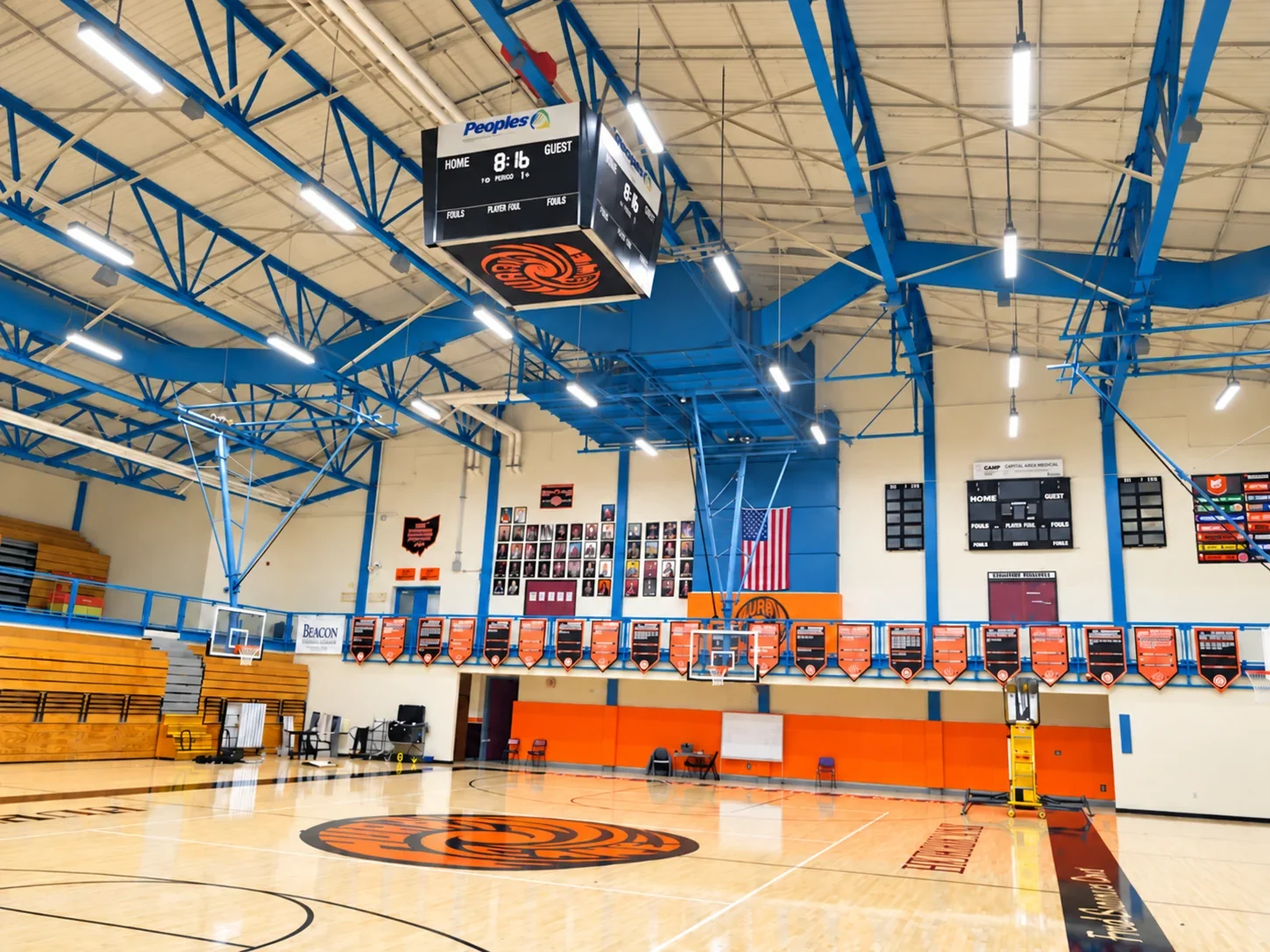 Wilmington High School main gym under new LED high bay lighting, blue roof trusses and the Hurricane logo at center court