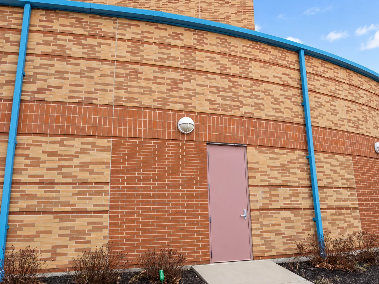 LED wall light above a side door on the curved brick exterior of a Wilmington City Schools building