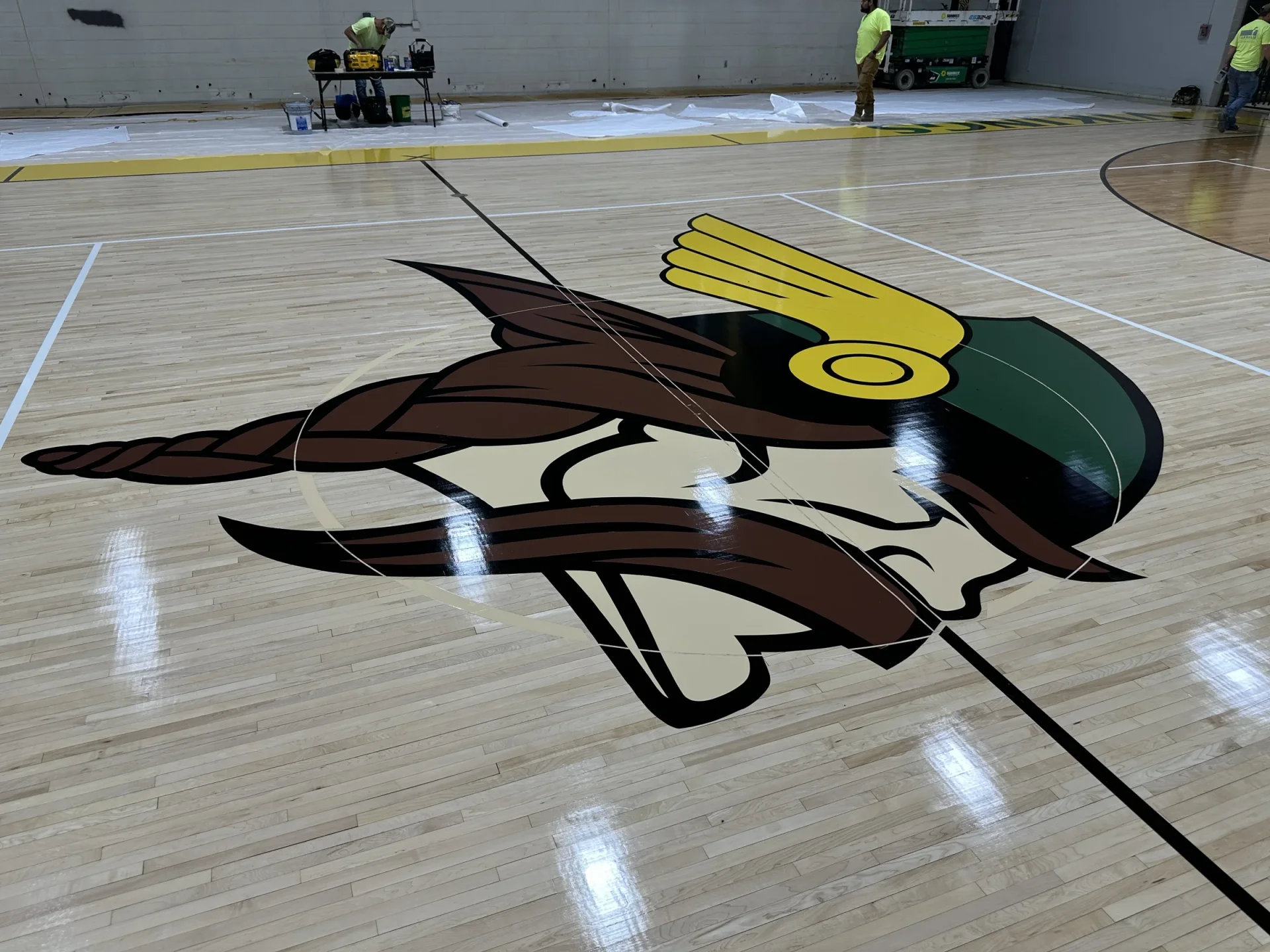 Newly painted Vikings logo at center court on the refinished Northland gym floor while crews finish the sidelines
